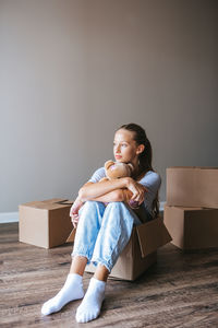 Portrait of young woman sitting against wall