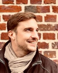 Portrait of smiling young man against brick wall