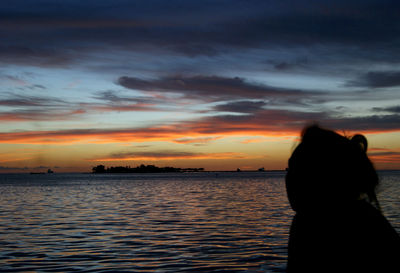 Silhouette woman by sea against sky during sunset