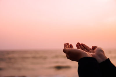 Cropped hands at beach during sunset