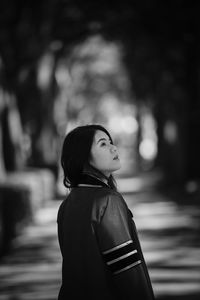 Side view of young woman looking away while standing on road