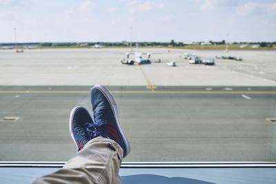 Low section of person with airplane on airport runway