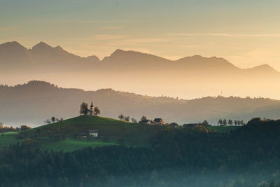 Scenic view of field and mountains against sky during sunset