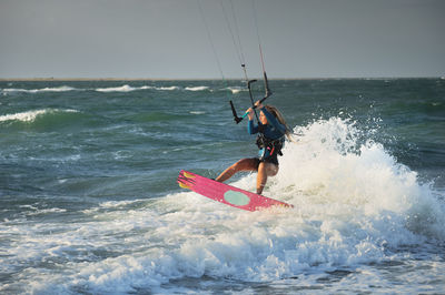 Professional kitesurfer caucasian woman rides big waves in windy weather. kitesurfing