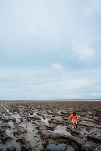 Child walking at beach against sky