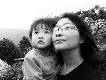 Close-up of mother and daughter looking away against sky