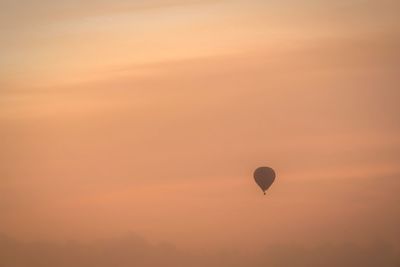 Silhouette hot air balloon against orange sky