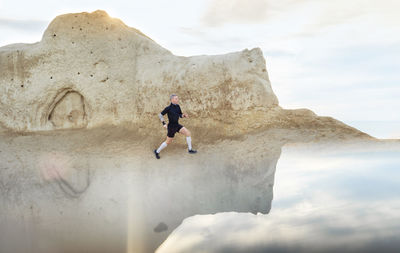 Low angle view of man on rock against sky