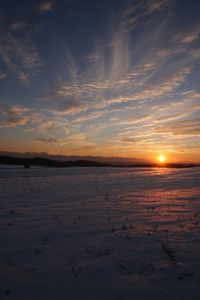 Scenic view of snow covered land against sky during sunset