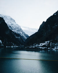 Scenic view of river by mountains against clear sky