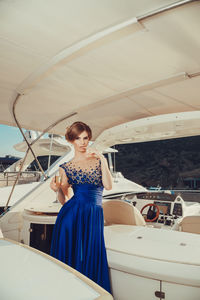 Beautiful young perfect girl in a dress and makeup, summer trip on a yacht with white sails 