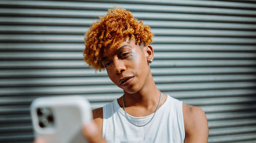 Young dark-skinned man posing at the street and taking selfie in the city background