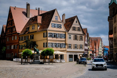 Cars on road by buildings against sky in city