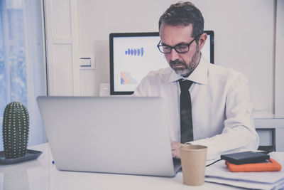 Portrait of businessman using laptop at office