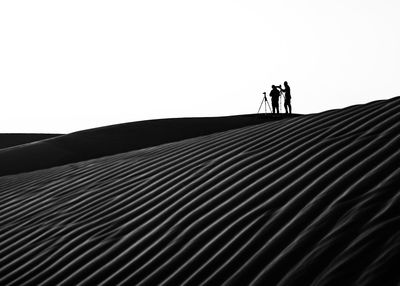 Low angle view of silhouette people walking against clear sky