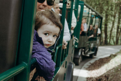 Portrait of a baby girl looking out of a train carriage.