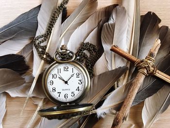 Close-up of clock with feathers on table