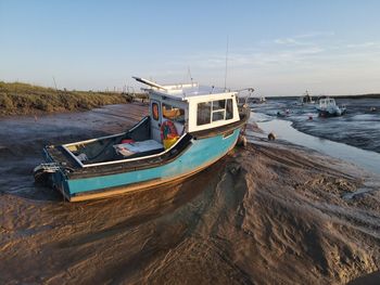 Boat moored on beach against sky