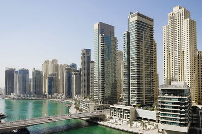 Modern buildings by harbor against sky in city