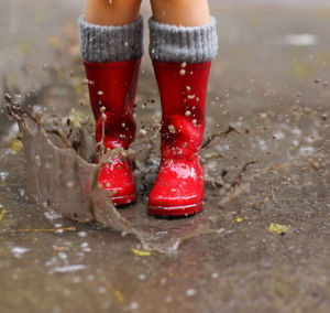 Low section of child standing in puddle
