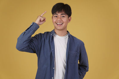 Portrait of smiling boy standing against yellow background