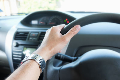 Cropped hand of man driving car