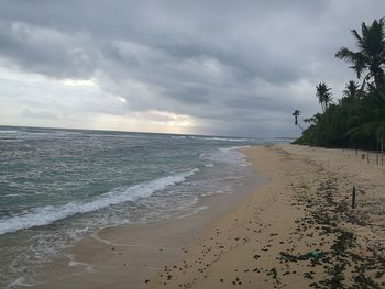 View of calm beach against cloudy sky