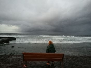 Rear view of woman sitting on beach