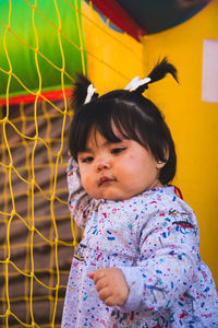 Close-up of baby girl against play equipment at playground