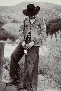 Rear view of cowboy sitting on field