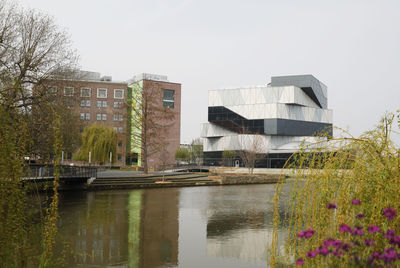 Buildings by river against clear sky