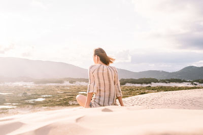 Rear view of woman standing on mountain against sky