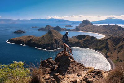 A man enjoying the view from the top of padar island using native indonesian woven cloth