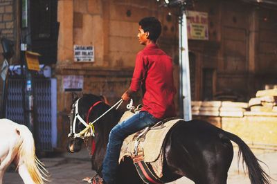 Man riding horse on street in city