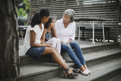 Three generation females sitting on steps at yard