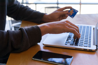 Midsection of man using laptop on table