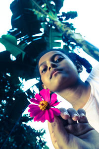 Portrait of beautiful young woman with pink flower