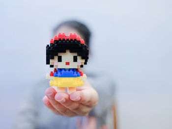 Close-up of hand holding dentures against white background
