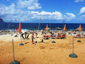 Deck chairs on beach against sky