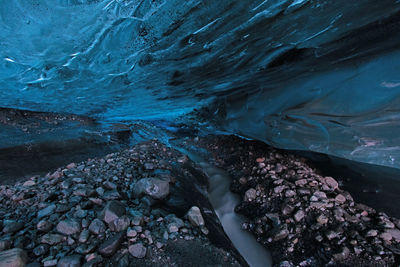 The ice cave of the flaajokull glacier in iceland, black volcanic rocks and blue iice