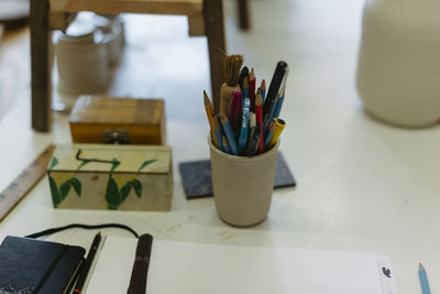 Close-up of colored pencils with paintbrush on table