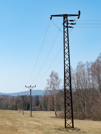 Low angle view of electricity pylon on field against sky