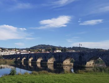 Arch bridge over river in city against sky