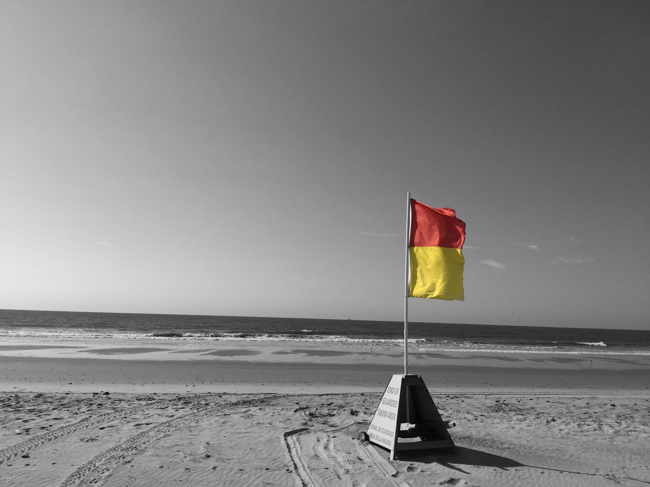 beach, sea, horizon over water, sand, shore, clear sky, copy space, flag, water, tranquility, tranquil scene, beach umbrella, sky, scenics, parasol, red, nature, absence, summer, day