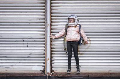 Full length of woman standing against closed shutter