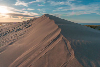 Sand dunes in desert against sky during sunset