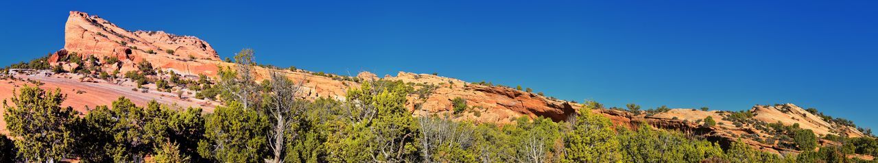 Panoramic view of rocky mountains against clear blue sky