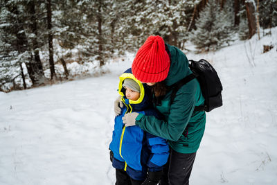 Rear view of boy standing on snow covered field