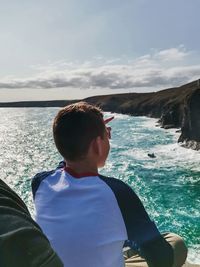 Man sitting in sea against sky