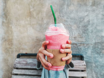 Midsection of woman holding ice cream cone against wall